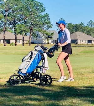 Hope Waggoner, Player Development Member, pushes clubs on the course – Greystone